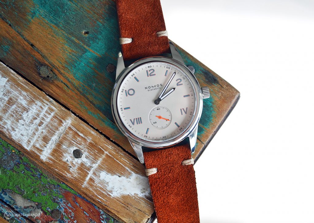 NOMOS Club Campus with rusty brown suede strap lying on colored table by WB Original